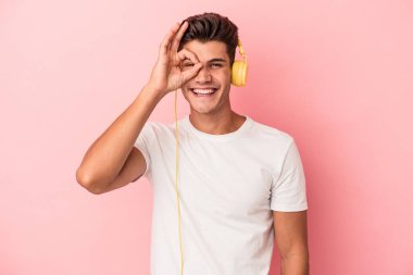 Pembe arka planda izole edilmiş müzik dinleyen beyaz bir adam heyecanlı..
