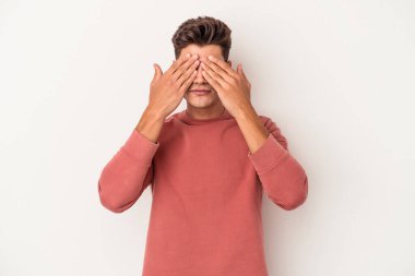 Beyaz arka planda izole edilmiş genç beyaz bir adam elleriyle gözlerini kapatmaktan korkuyor..