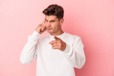 Pembe arka planda izole edilmiş genç beyaz bir adam parmağıyla tapınağı işaret ediyor, düşünüyor ve bir göreve odaklanıyor..