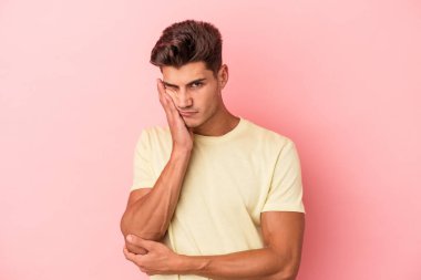 Pembe arka planda izole edilmiş genç beyaz adam sıkılmış, yorgun ve dinlenmeye ihtiyacı var..