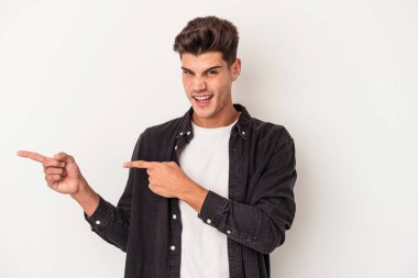 Beyaz arka planda izole edilmiş genç beyaz bir adam işaret parmağıyla fotokopi alanını işaret ederek heyecan ve arzusunu ifade ediyor..