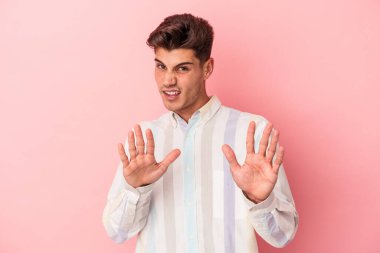 Pembe arka planda izole edilmiş genç beyaz bir adam tiksinti belirtisi gösteren birini reddediyor..