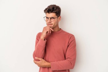 Beyaz arka planda soyutlanmış genç beyaz bir adam düşünüyor ve yukarı bakıyor, yansıtıyor, düşünüyor, hayal kuruyor..