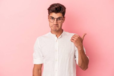 Pembe arka planda izole edilmiş genç beyaz adam işaret parmağıyla fotokopi alanını işaret ederek şok oldu..