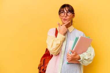 Arjantinli genç bir bayan, sarı arka planda izole edilmiş şüpheli ve kuşkulu bir ifadeyle yana bakıyor..
