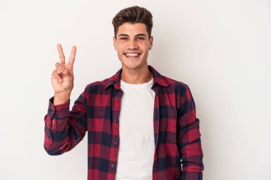 Beyaz arka planda izole edilmiş genç beyaz bir adam neşeli ve kaygısız parmakları olan bir barış sembolü gösteriyor..