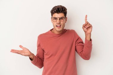 Beyaz arka planda izole edilmiş genç beyaz bir adam elinde bir ürün tutuyor ve.