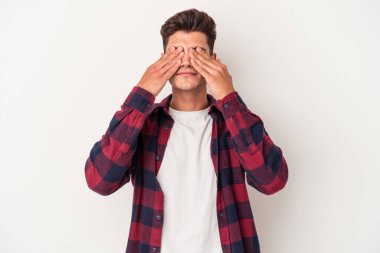 Beyaz arka planda izole edilmiş genç beyaz bir adam elleriyle gözlerini kapatmaktan korkuyor..