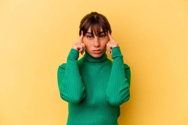 Sarı arka planda izole edilmiş genç Arjantinli kadın bir göreve odaklanmış, işaret parmaklarını işaret ediyor..