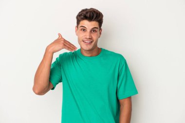 Beyaz arka planda izole olmuş genç beyaz bir adam bir şeye gülüyor, ağızlarını ellerle kapatıyor..