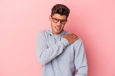 Pembe arka planda izole edilmiş, omuz ağrısı olan genç beyaz bir adam..