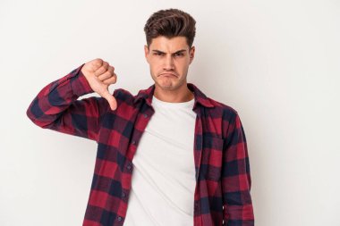 Beyaz arka planda izole edilmiş genç beyaz adam baş parmağını aşağı gösteriyor, hayal kırıklığı konsepti..