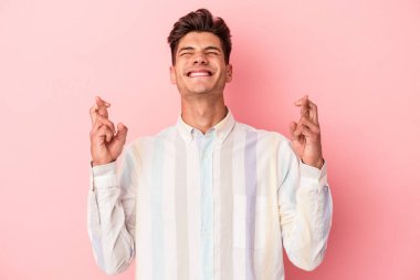 Pembe arka planda izole edilmiş beyaz bir adam şans getirsin diye dua ediyor.