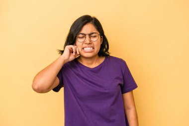 Sarı arka planda izole edilmiş, parmaklarıyla kulaklarını kapatan genç Latin bir kadın gürültülü bir ortam yüzünden stresli ve çaresiz..