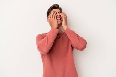 Beyaz arka planda izole olmuş genç beyaz bir adam ellerini başının üstünde tutarak neşeyle gülüyor. Mutluluk kavramı.