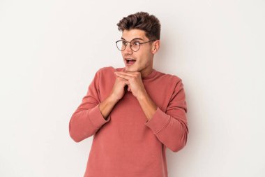 Beyaz arka planda izole edilmiş genç beyaz bir adam şans için dua ediyor, şaşırmış ve ağzını açıp önüne bakıyor..