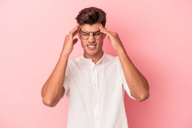 Pembe arka planda izole edilmiş genç beyaz adam tapınaklara dokunuyor ve baş ağrısı çekiyor..