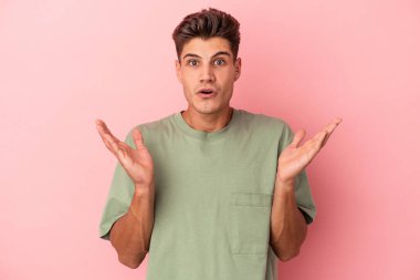 Pembe arka planda izole edilmiş genç beyaz adam şaşırdı ve şok oldu..