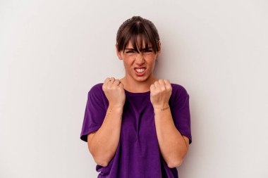 Beyaz arka planda izole edilmiş genç Arjantinli kadın kameraya yumruk sallıyor, agresif yüz ifadesi var..