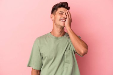 Pembe arka planda izole olmuş genç beyaz bir adam gülüyor, kaygısız, doğal bir duygu..