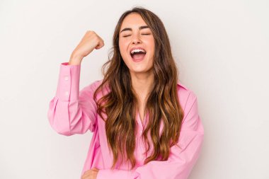 Beyaz arka planda izole edilmiş genç beyaz kadın zaferi, tutkuyu ve coşkuyu kutluyor, mutlu bir ifade..