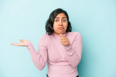 Mavi arka planda izole edilmiş genç Latin kadın parasız olduğunu gösteriyor..