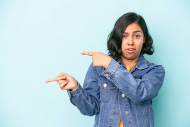 Mavi arka planda izole edilmiş genç Latin kadın işaret parmaklarıyla fotokopi alanını işaret ederek heyecan ve arzuyu ifade ediyor..