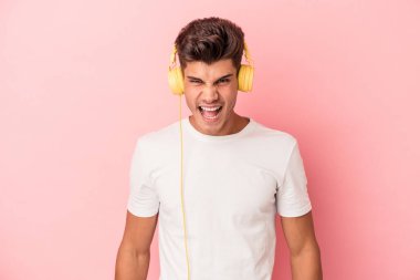 Pembe arka planda izole edilmiş müzik dinleyen genç beyaz adam çok sinirli ve agresif çığlıklar atıyor..