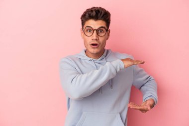 Pembe arka planda izole edilmiş genç beyaz adam elleri arasında bir fotokopi alanı tutuyor..