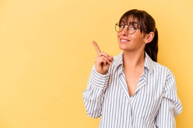 Sarı arka planda izole edilmiş genç Arjantinli kadın bir numarayı parmağıyla gösteriyor..