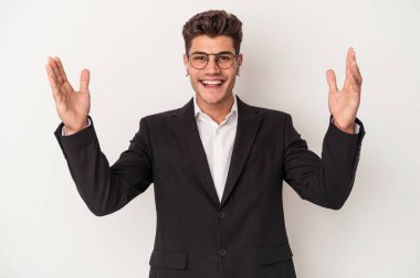 Beyaz arka planda izole edilmiş kulaklık takan genç beyaz iş adamı hoş bir sürpriz alıyor, heyecanlı ve el kaldırıyor..