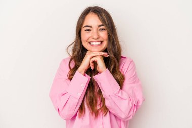 Beyaz arka planda izole edilmiş genç beyaz kadın ellerini çenesinin altında tutuyor, mutlu bir şekilde yana bakıyor..