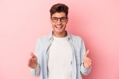 Pembe arka planda izole edilmiş beyaz bir adam iki eliyle bir şey tutuyor, ürün sunumu..