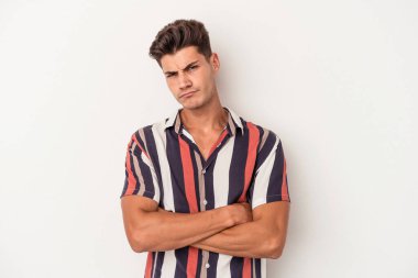 Beyaz arka planda izole edilmiş, hoşnutsuzca kaşlarını çatmış, kollarını kavuşturmuş genç beyaz bir adam..