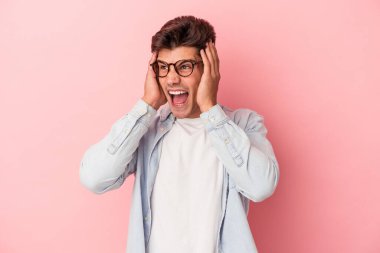 Kafkasyalı genç adam pembe arka planda izole edilmiş kulakları kulaklarıyla kapatıyor çok fazla ses duymamaya çalışıyor..