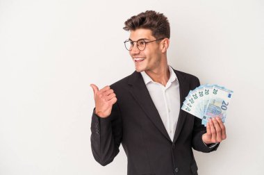 Elinde banknotlar tutan Kafkasyalı genç bir adam beyaz arka plandaki izole edilmiş başparmak uzakta, gülen ve kaygısız..
