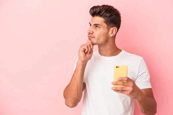 Młody Biały Mężczyzna Trzyma Telefon Komórkowy Odizolowany Różowym Tle Patrząc — Zdjęcie stockowe