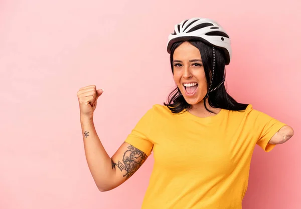 勝利の後に拳を上げピンクの背景に隔離された自転車のヘルメットを身に着けている一本の腕を持つ若い白人女性 勝者の概念 — ストック写真