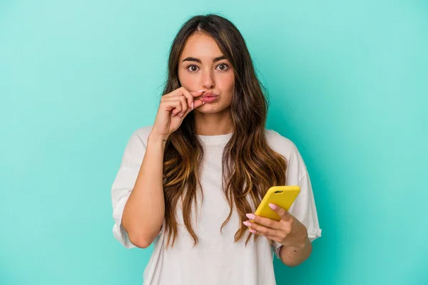 Mladá Běloška Drží Mobilní Telefon Izolovaný Modrém Pozadí Prsty Rtech — Stock fotografie