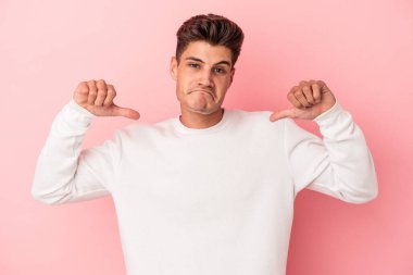 Pembe arka planda izole edilmiş genç beyaz adam gururlu ve kendinden emin hissediyor, örnek olarak.