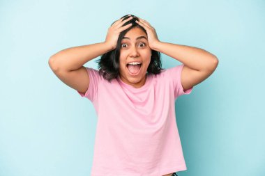 Genç Latin bir kadın mavi arka planda izole edilmiş bağırıyor, çok heyecanlı, tutkulu, bir şeyden memnun..
