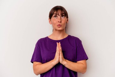 Beyaz arka planda izole edilmiş genç Arjantinli bir kadın el ele dua ederken, kendine güveniyor..