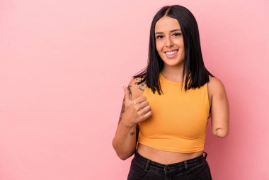 Tek kollu beyaz bir kadın pembe arka planda izole edilmiş gülümsüyor ve başparmağını kaldırıyor.