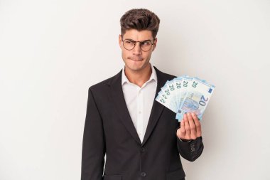 Beyaz arka planda izole edilmiş banknotları tutan genç beyaz bir adam kafası karışmış, şüpheli ve güvensiz hissediyor..