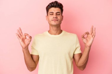 Pembe arka planda izole edilmiş genç beyaz adam sıkı çalışma gününden sonra rahatlıyor. Yoga yapıyor..