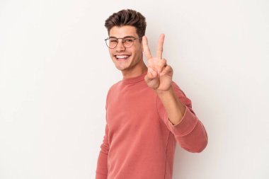 Beyaz arka planda izole edilmiş genç beyaz bir adam neşeli ve kaygısız parmakları olan bir barış sembolü gösteriyor..