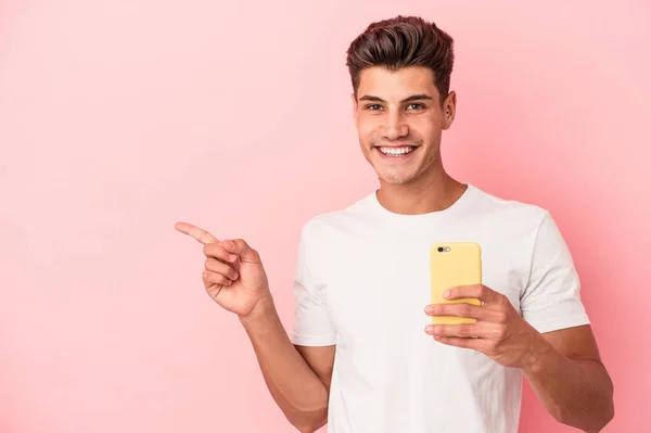 Jovem Caucasiano Segurando Telefone Celular Isolado Fundo Rosa Sorrindo Apontando — Fotografia de Stock