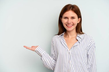 Mavi arka planda izole edilmiş genç bir İngiliz kadın bir avuç içinde fotokopi alanı ve belinde bir el daha olduğunu gösteriyor..