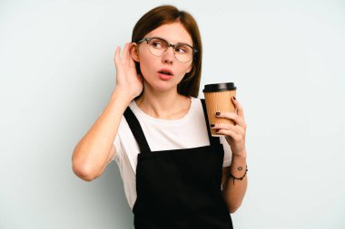 Restoran garsonu elinde kahve tutan kadın mavi arka planda izole edilmiş bir şekilde bir dedikoduyu dinlemeye çalışıyor..