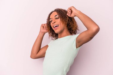 Pembe arka planda izole edilmiş genç Latin transseksüel kadın özel bir günü kutluyor, atlıyor ve enerjiyle kollarını kaldırıyor..